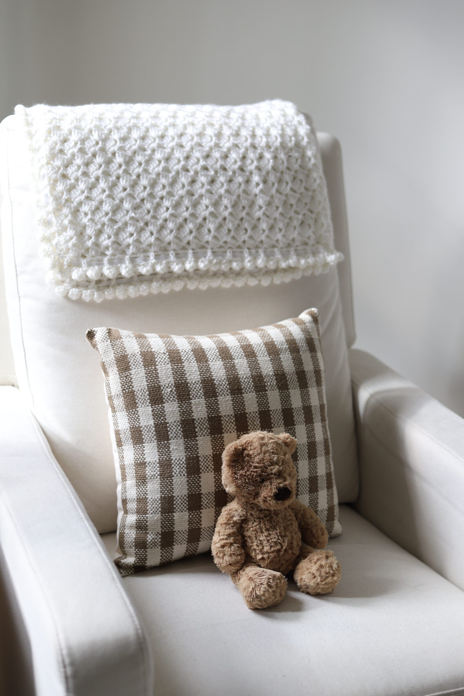 neutral nursery chair recliner with brown gingham pillow and jellycat bear